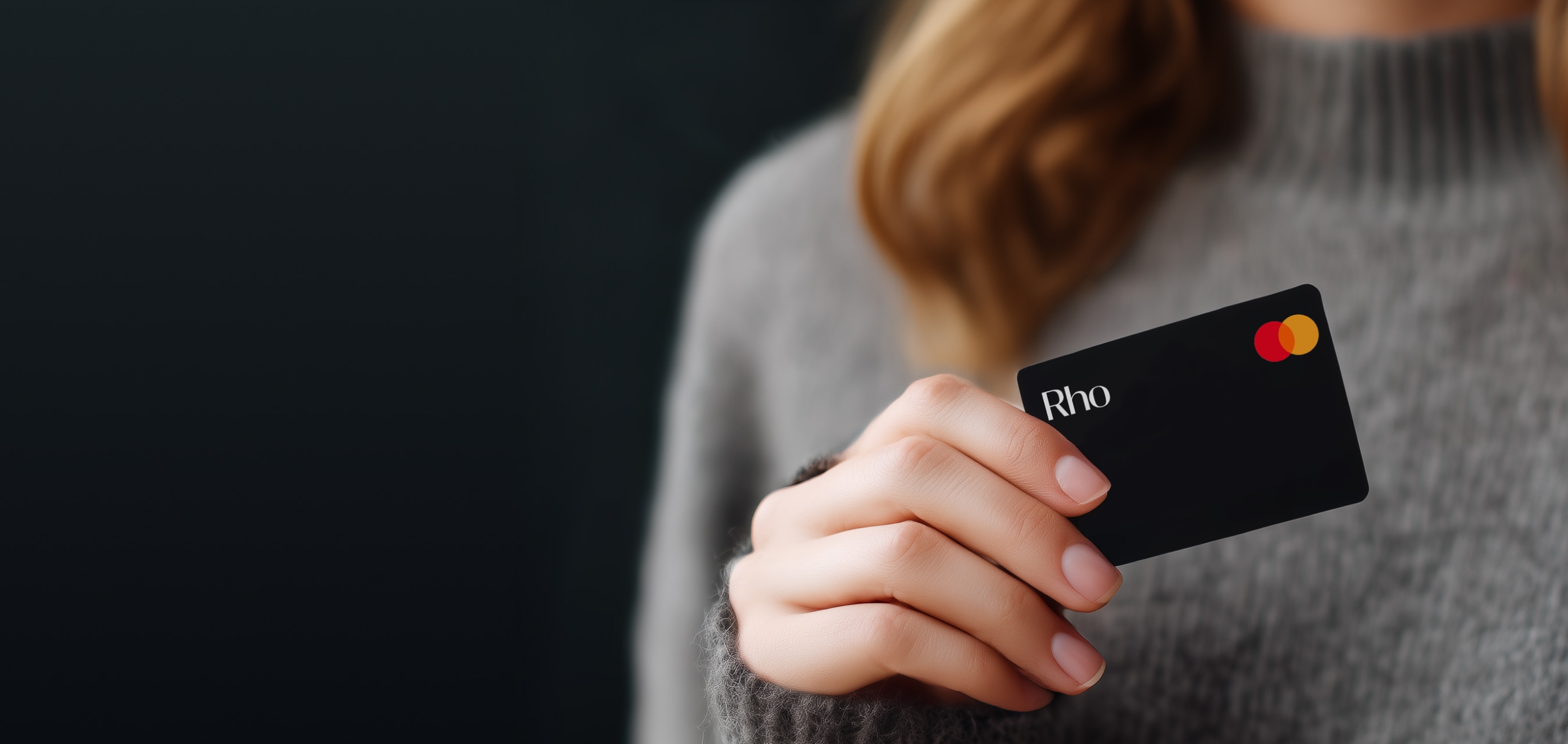 Woman wearing gray sweater holding a black Rho credit card
